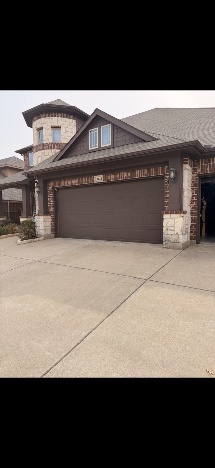 Brown residential garage door on a brick and stone home